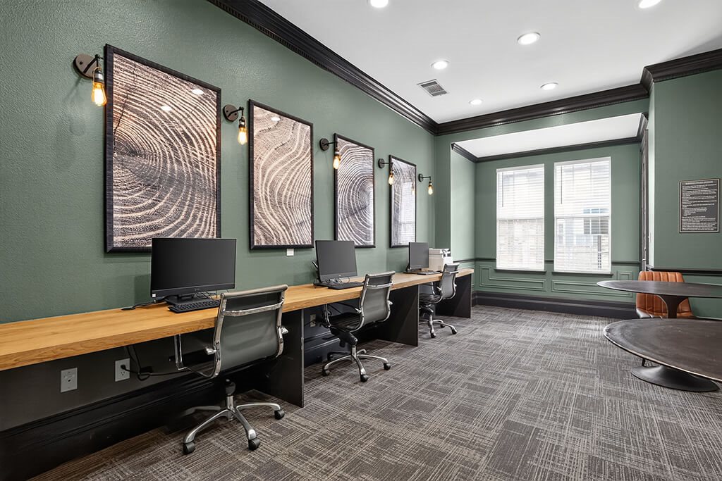A room with a green wall and a long wooden table with chairs.